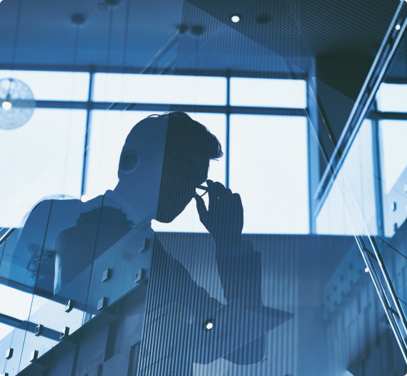 A imagem mescla Um homem vestido com terno e gravata segurando o oculos e fundo com alguns prédios 